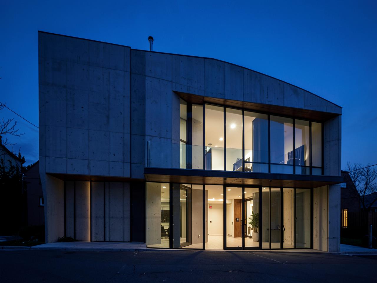 Concrete and glass house lit from within at blue hour